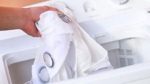 pessoa colocando cortina na máquina de lavar